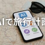 地図の上に置かれたスマートフォンの画面に、AIによる旅行計画アプリのアイコンが表示されており、画面の中央に“AIで旅行計画”の日本語テキストが重ねられている。隣には黒いサングラスが置かれていて、旅行の雰囲気を演出しているリアルな構図の横長画像。」