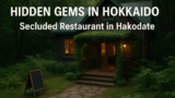 AI関連のブログ A cozy, hidden restaurant in the forested countryside of Hokkaido, Japan. The two-story wooden building is surrounded by lush greenery, with warm lights glowing from its windows and ivy covering the entrance. A stone path leads to the entrance, giving the scene a peaceful and secluded ambiance.