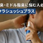 中年男性が「耳ウラシュッシュプラス」のスプレーを耳の裏に使用している様子。白いボトルを手に持ち、清潔感のある柔らかい背景の中で加齢臭ケアをしているリアルな場面。