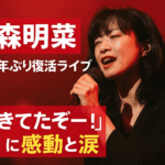 16年ぶりにライブ出演した中森明菜さんをイメージした女性歌手が、赤いステージライトの中でマイクを手に歌う感動的なアイキャッチ画像。大きな日本語テキストで「生きてたぞー！」の言葉が強調されている。